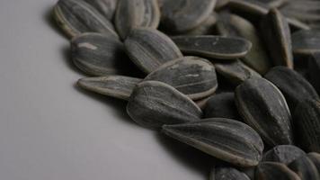 Tiro cinematográfico, giratorio de semillas de girasol sobre una superficie blanca - semillas de girasol 012
