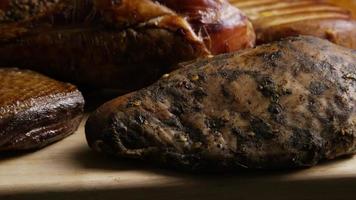 Rotating shot of a variety of delicious, premium smoked meats on a wooden cutting board - FOOD 067 video