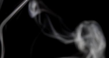 Blurred smoke in background and focused smoke in foreground dancing in darkness in 4K video