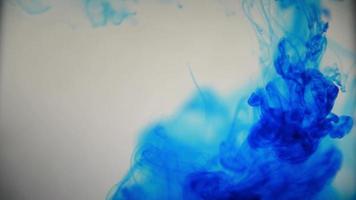 tinta de tinta de cor azul derramando sobre o vidro com gotas de tinta caindo e explosão de fumaça abstrata.