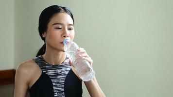 Aziatische sportvrouw drinkwater na comout