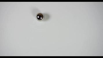 Cuatro bolas de barril de acero moviéndose sobre una superficie blanca en diferentes caminos en 4k video