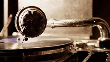 Extreme close up of record player needle and vinyl disc spinning with bright little from left side in 4K video