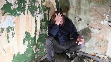 homme déprimé et en colère est assis dans le coin dans une maison abandonnée