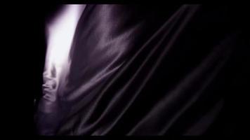 Dark purple fabric moved by the wind showing waves moving like fire in 4K video