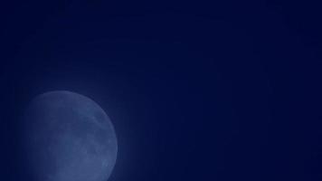Blurried night scene of waxing moon moving in dark sky in 4K video