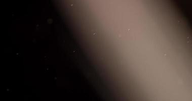 pequeñas partículas que cruzan la escena subiendo sobre fondo negro con luz sepia en 4k video