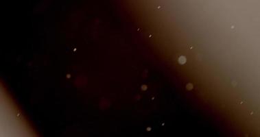 Few defocused particles moving to upper corners on background with two light rays in 4K video
