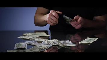 Hands of a man picking up 100 Bills off of a Reflective Surface - MONEY 0040 video