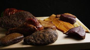 Tiro giratório de uma variedade de deliciosas carnes defumadas premium em uma tábua de madeira - comida 062 video