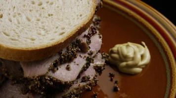 roterend schot van heerlijke, premium pastrami-sandwich naast een klodder dijon-mosterd - voedsel 041