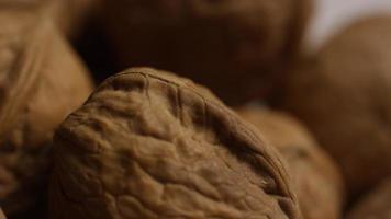 Cinematic, rotating shot of walnuts in their shells on a white surface - WALNUTS 078
