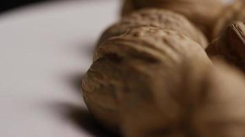 Cinematic, rotating shot of walnuts in their shells on a white surface - WALNUTS 038 video