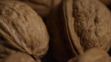 Cinematic, rotating shot of walnuts in their shells on a white surface - WALNUTS 023