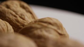 filmische, roterende opname van walnoten in hun schelpen op een wit oppervlak - walnoten 037 video