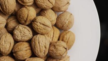 Cinematic, rotating shot of walnuts in their shells on a white surface - WALNUTS 046