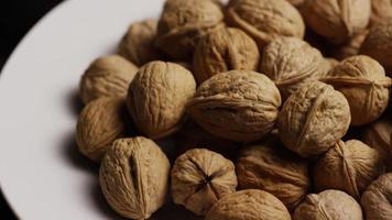 Cinematic, rotating shot of walnuts in their shells on a white surface - WALNUTS 071 video