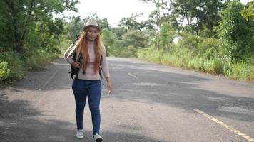 Viajero mujer mochilero haciendo autostop en la carretera y caminando. video
