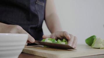 close-up van chief vrouw salade gezond voedsel maken en paprika hakken op snijplank.