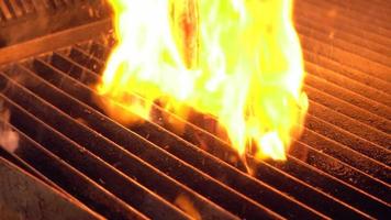 chefe de cozinha coloca um pedaço de carne crua na grelha de fumar quente com fogo por baixo usando uma pinça de metal, close-up em câmera lenta.