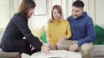 heureux jeune couple asiatique et agent immobilier. video