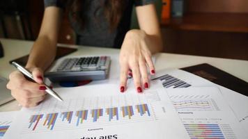 Une femme à l'aide de ses mains pour la comptabilité dans un bureau à l'aide d'un ordinateur portable et d'une calculatrice video