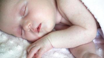 närbild av nyfödd liten flicka sover på sängen, söta drömmar om liten baby, hälsosam sömn. video