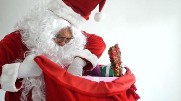 Santa Claus wearing a red suit and preparing a gift bag