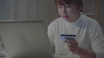 mooie Aziatische vrouw die online met creditcard winkelt. video