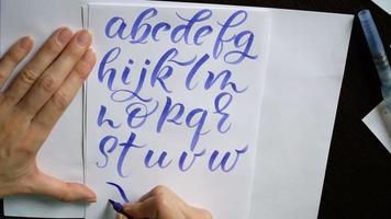 Frauenhand schreibt ein kalligraphisches Alphabet
