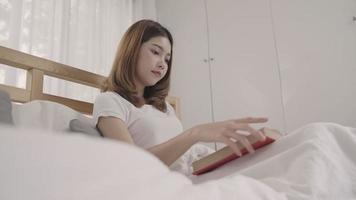 junge asiatische Frau liest ein Buch vor dem Schlafengehen