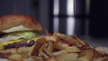 Ketchup falls on a pile of french fries in slow-motion video