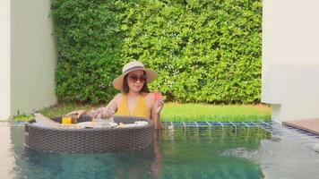 Young Asian woman enjoying a floating breakfast in the swimming pool video