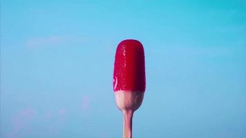 El helado rojo se está derritiendo sobre un fondo azul. video