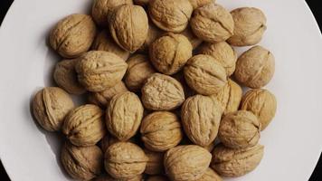 Cinematic, rotating shot of walnuts in their shells on a white surface - WALNUTS 042