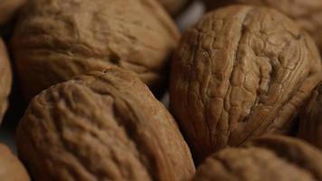 Cinematic, rotating shot of walnuts in their shells on a white surface - WALNUTS 021 video