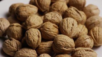 Cinematic, rotating shot of walnuts in their shells on a white surface - WALNUTS 070 video