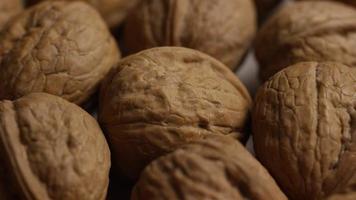 Cinematic, rotating shot of walnuts in their shells on a white surface - WALNUTS 016 video