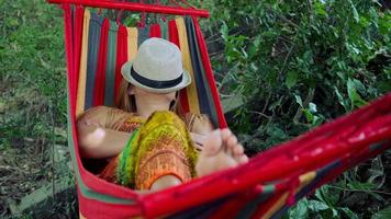 Mujer joven durmiendo en una hamaca con sombrero cubriendo la cara video