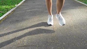 ralenti - jeune femme asiatique en cours d'exécution sur le trottoir le matin. jeune femme asiatique de sport en cours d'exécution dans le parc. fitness en cours d'exécution des gens de sport et concept de mode de vie sain. video