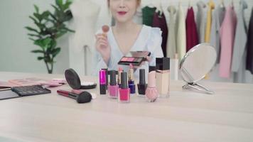 Beauty blogger present beauty cosmetics sitting in front camera for recording video. Beautiful asian woman use cosmetics while review make up tutorial broadcast live video to social netcom by internet.