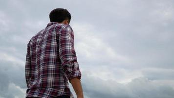 L'homme se tient détendu avec les mains levées en l'air dans le parc video