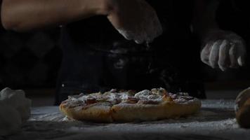 Zeitlupe der Hände einer Frau, die Mehl über eine Pizza sieben video