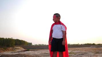 Silhouette of a boy having fun dressed as a superhero running in a field video