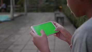 kinderen jongen hand met behulp van slimme telefoon spel online spelen op groen scherm. video