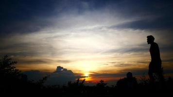 silhuetas de relaxar o homem com o fundo do céu do sol. video