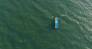 Draufsicht auf ein blaues Boot, das im Meer segelt