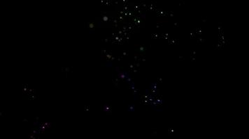 A mix of colorful glowing particles in motion on a dark background video