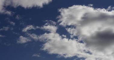 time-lapse van grote grijze en witte wolken die weggaan van de camera op blauwe hemel in 4k video