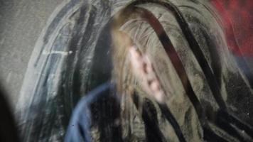 homem deprimido e zangado está sentado em frente a seu reflexo em uma velha casa abandonada